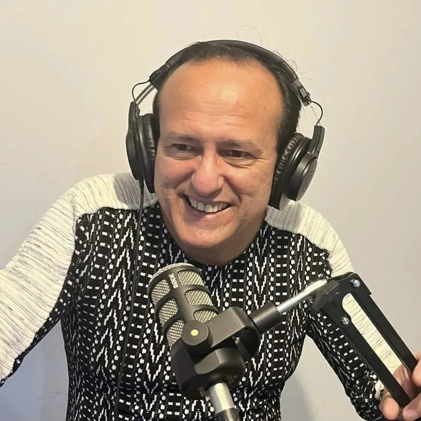Edilásio Jr. de fones de ouvido diante do microfone, no estúdio da rádio no Reino Unido