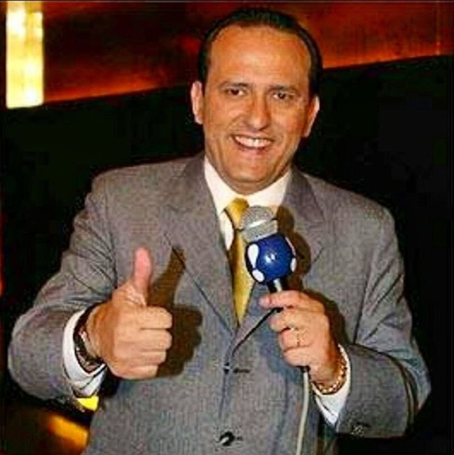 Edilásio Jr. de terno e gravata dourada com o microfone da RedeTV!